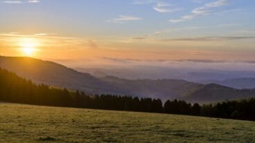 Zonsopgang boven een veld met heuvels op de achtergrond op de Uplandsteig in het Sauerland
