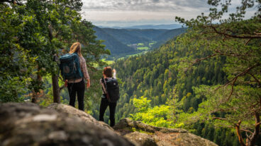 Twee wandelaars staan op de Bildsteinfelsen en kijken het Albdal in