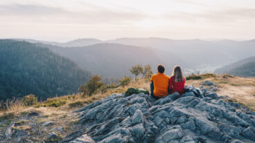 Twee wandelaars zitten op de Scheibenfelsen en kijken uit over het dal bij Bernau