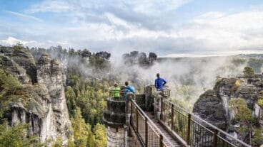 Wandelaars staan op een uitkijkplatform op de Basteibrug in het Nationaal Park Saksisch Zwitserland
