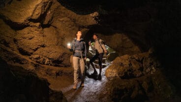 Twee wandelaars verkennen met zaklampen de Mühlsteinhöhle in de Rother Kopf
