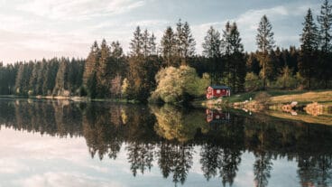 Een hut bij een spiegelgladde Ziegenberger Teich die het landschap bij Buntenbock weerspiegelt
