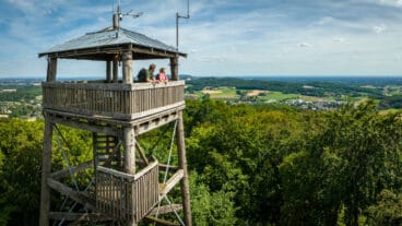 Twee wandelaars staan boven op de houten Luisenturm en kijken uit over het Teutoburger Woud bij Borgholzhausen